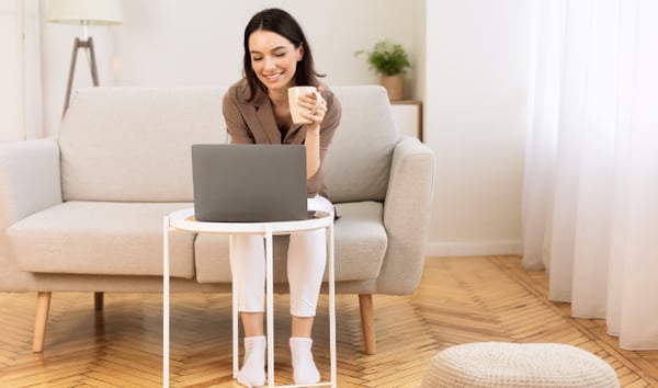 Change management professional sat on a sofa with coffee at a laptop